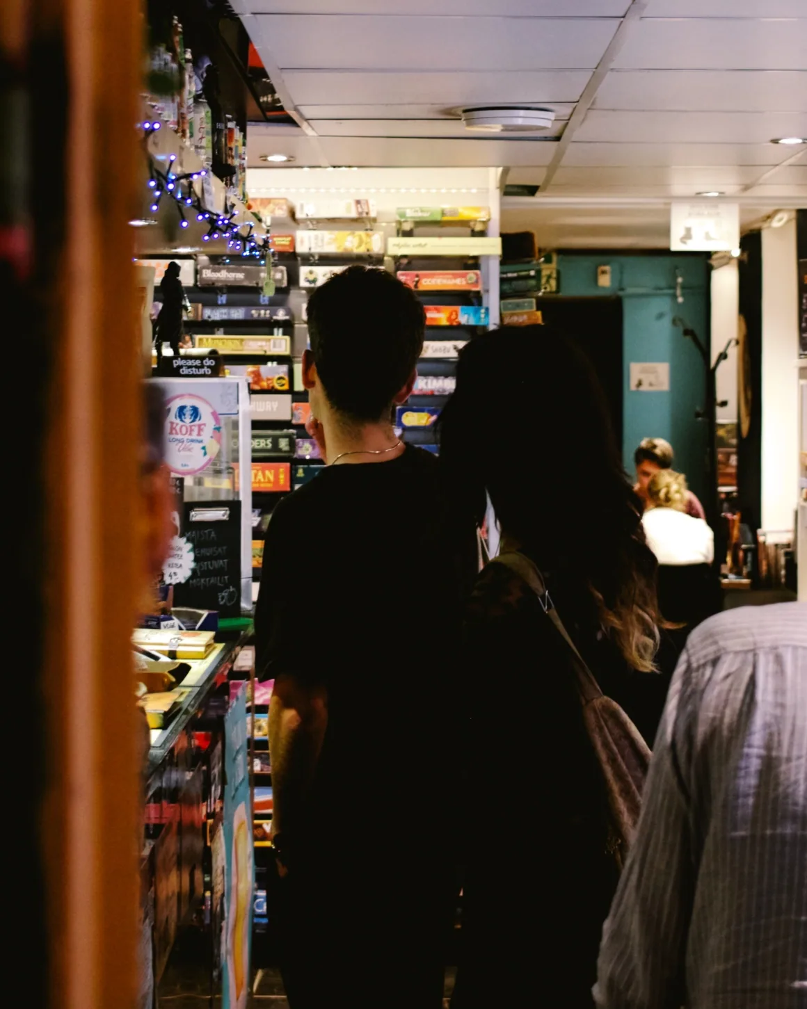 Guests and shelves inside Café Boardgame's game room