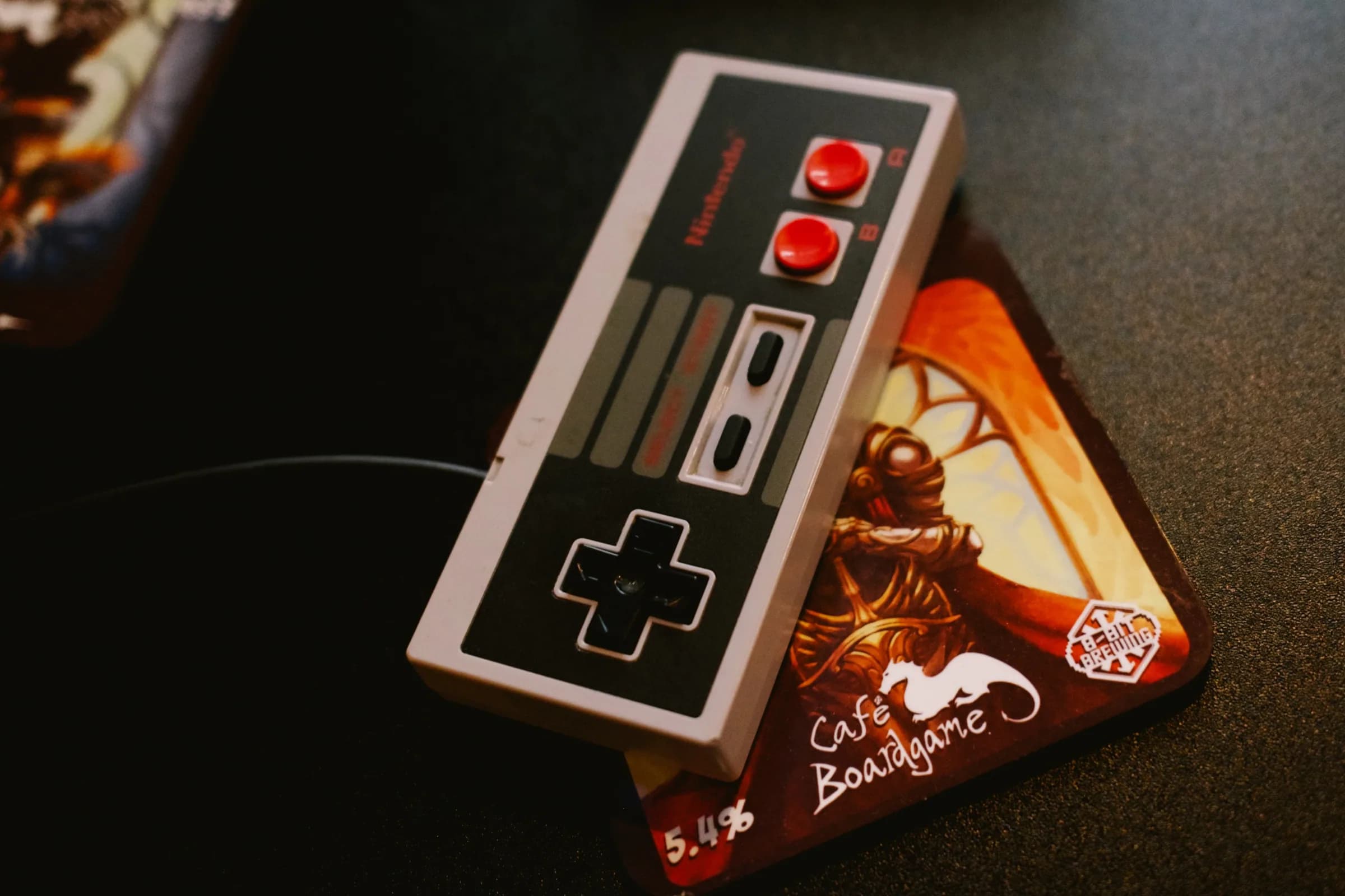 A retro game controller and Café Boardgame card on a game table