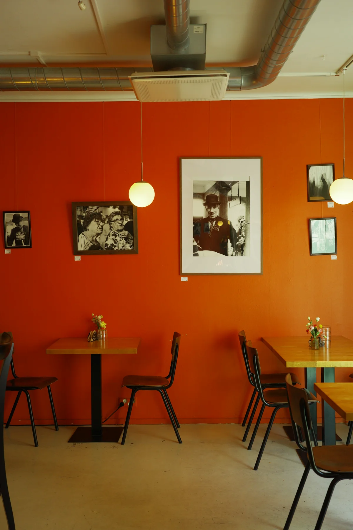 Framed artwork on an orange wall above tables at Casa Alejandro