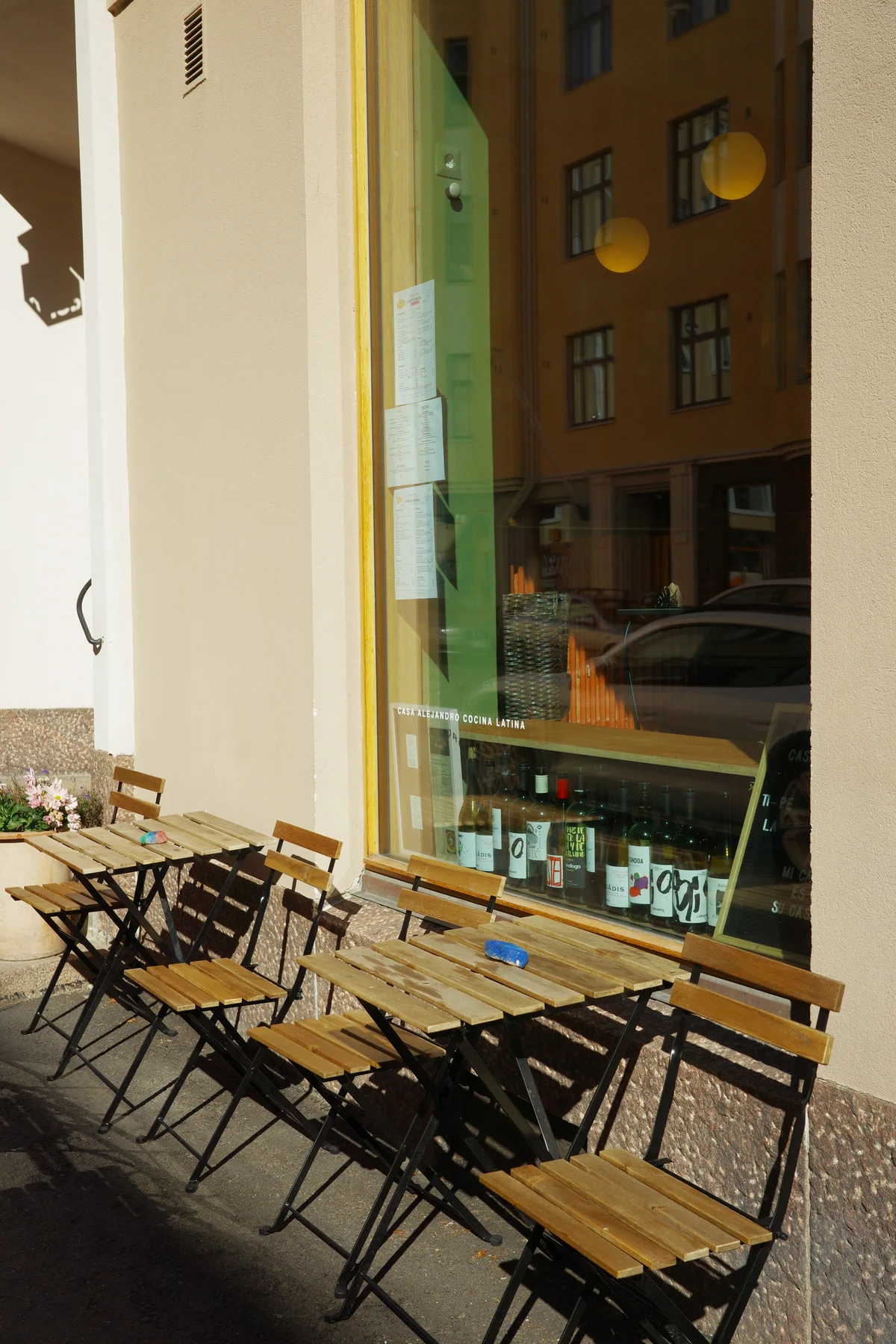 Outdoor tables and folding chairs along Casa Alejandro's window