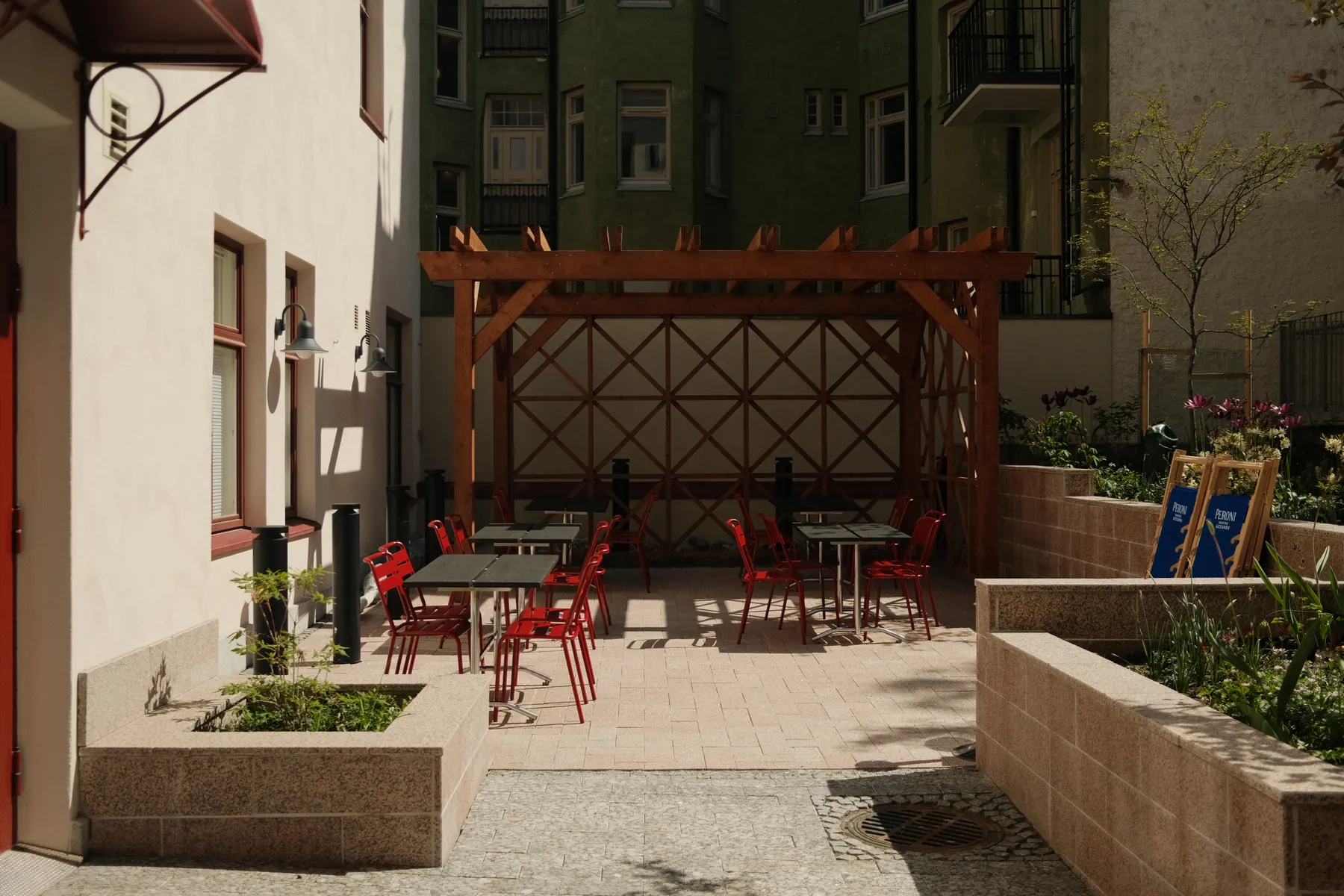 Focaccina's courtyard terrace with red chairs and sunlit planters in Helsinki
