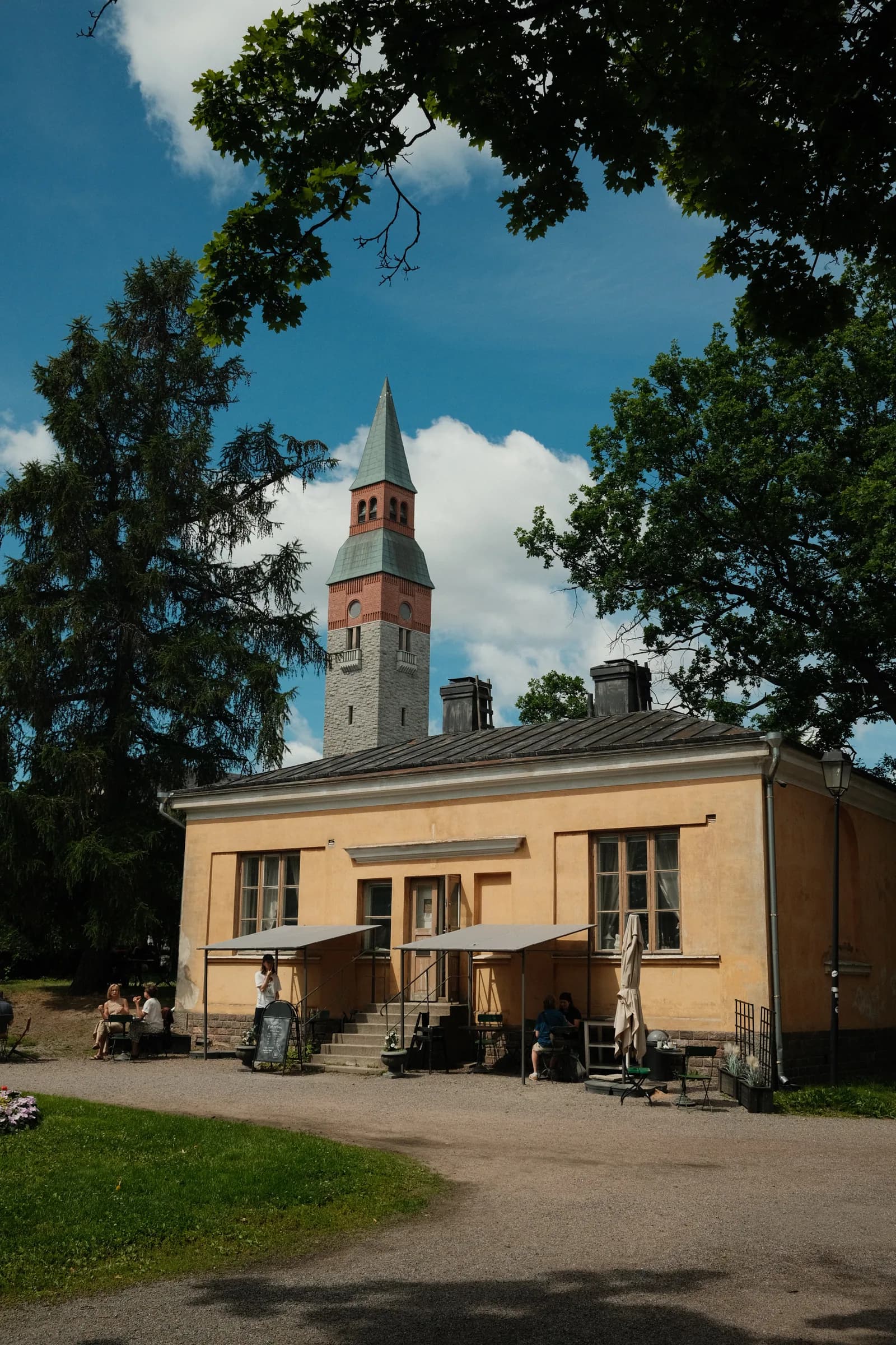 Kahvila Rakastan yellow building exterior with a church tower visible behind it
