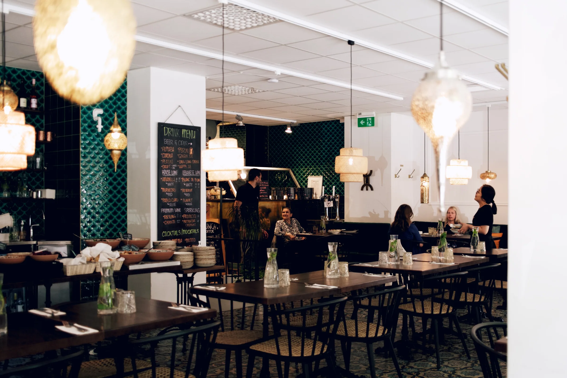 Levant dining room with green tile, pendant lights, and prepared tables