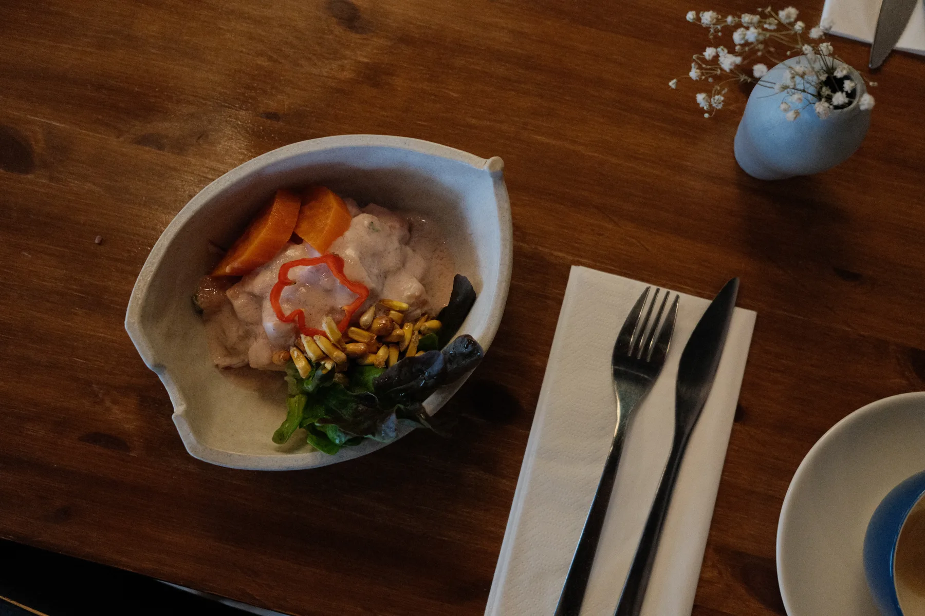 Ceviche served in a shell-shaped bowl on a dark wooden table at Tinku